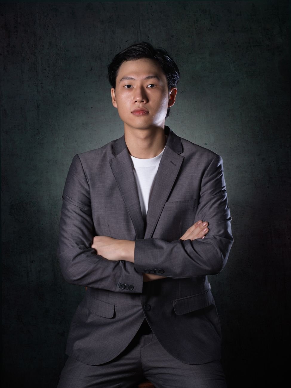 Professional portrait of a confident businessman in a grey suit with a dark background.